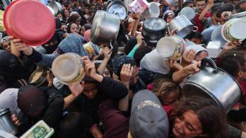 Los palestinos se agolpan para recibir una comida caliente de una cocina benéfica en el campo de refugiados de Nuseirat, en la Franja de Gaza, sitiada por Israel.