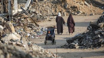 Un niño palestino sentado en un cochecito junto a una carretera destruida en Nuseirat, Franja de Gaza.