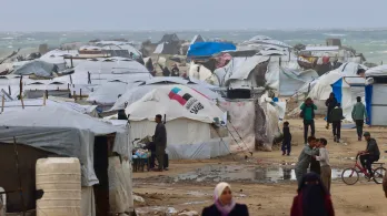 Los desplazados palestinos caminan cerca de tiendas de campaña y refugios improvisados mientras la región sufre las frías condiciones invernales en el campo de refugiados de Al-Mawasi, en el sur de la Franja de Gaza. 