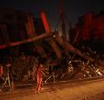 Palestinos pasan junto a un edificio destruido en el campo de refugiados de Al-Bureij, en el centro de la Franja de Gaza, durante la noche.
