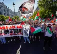 Manifestantes pro palestinos enarbolan banderas y pancartas palestinas tras invadir la calle y obligar a los organizadores de la carrera a suspender la 21.ª y última etapa de la Vuelta a España 2025, una carrera de 101 km entre Alalpardo y Madrid, en Madrid.