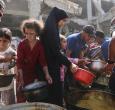 Los palestinos desplazados de Gaza se reúnen para recibir raciones de comida frente a la mezquita Imam al Shafi'i, dañada, donde se han refugiado familias, en el barrio de Zeitoun de la ciudad de Gaza.