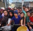Niños palestinos se reúnen para recibir raciones de comida de un comedor benéfico en Nuseirat, en la Franja de Gaza central.