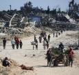 Vertriebene Palästinenser gehen an zerstörten Gebäuden vorbei, als sie in ihre Häuser im Gebiet al-Zahra nördlich des Flüchtlingslagers Nuseirat im zentralen Gazastreifen zurückkehren.