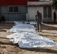 Un hombre observa las bolsas con restos humanos tras la exhumación de las tumbas por parte de la defensa civil en el interior del Hospital Bautista Árabe Al-Ahli para trasladar los restos a los cementerios oficiales de la ciudad de Gaza. 