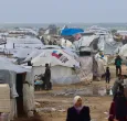 Los desplazados palestinos caminan cerca de tiendas de campaña y refugios improvisados mientras la región sufre las frías condiciones invernales en el campo de refugiados de Al-Mawasi, en el sur de la Franja de Gaza. 