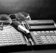 calculadora financiera antigua, gafas y lapicero
