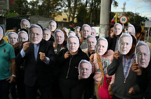 Personas con máscaras de Álvaro Uribe.