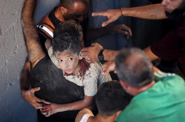 Palestinos transportan a un niño herido en el lugar donde se produjo un ataque israelí que destruyó varios edificios en el barrio de Al-Rimal, en la ciudad de Gaza.