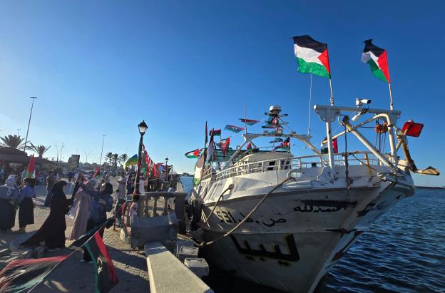 Personas posan para una foto frente al barco Omar al-Mukhtar, un barco libio que zarpó el 17 de septiembre para unirse a la Flotilla Global Sumud, en el puerto de Trípoli.