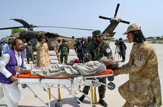 Voluntarios afganos y personal de seguridad talibán transportan a una víctima del terremoto evacuada por un helicóptero militar desde el distrito de Nurgal, en la provincia de Kunar, tras su llegada a Jalalabad para recibir asistencia médica.