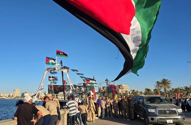 Personas posan para una foto frente al barco Omar al-Mukhtar, un barco libio que zarpó el 17 de septiembre para unirse a la Flotilla Global Sumud, en el puerto de Trípoli. 