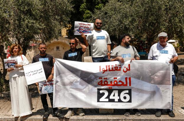 Periodistas árabe-israelíes levantan pancartas y una bandera palestina durante una manifestación en solidaridad con sus compañeros de profesión fallecidos en los ataques israelíes en la Franja de Gaza, en la ciudad norteña de Nazaret, el