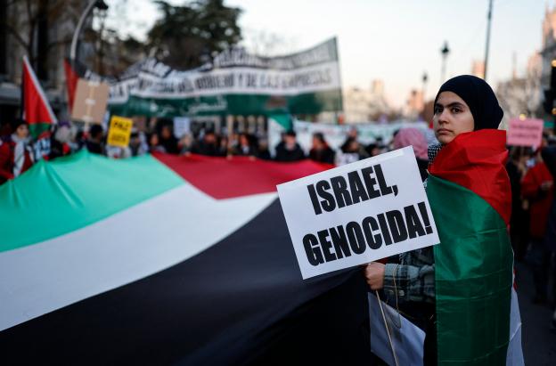 Una mujer sostiene un cartel con el lema «¡Israel, genocidio!» durante una manifestación en apoyo al pueblo palestino y para exigir el fin de la guerra en Gaza, celebrada en Madrid.