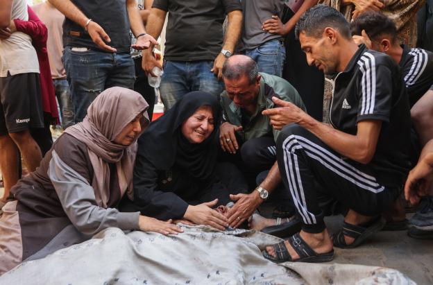 Los palestinos lloran junto al cadáver de un familiar asesinado en los ataques israelíes contra la ciudad de Gaza al amanecer, en el hospital Al-Shifa. 