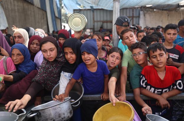 Niños palestinos se reúnen para recibir raciones de comida de un comedor benéfico en Nuseirat, en la Franja de Gaza central.