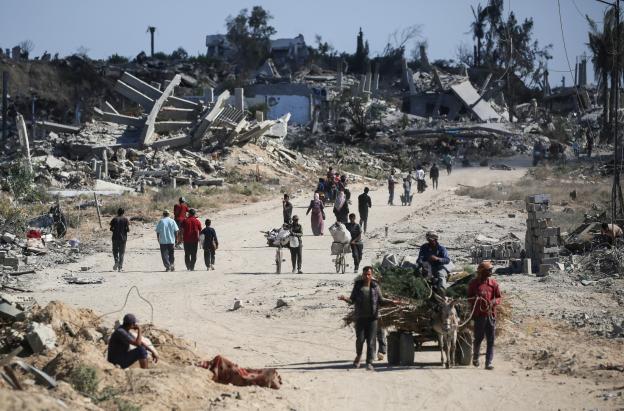 Vertriebene Palästinenser gehen an zerstörten Gebäuden vorbei, als sie in ihre Häuser im Gebiet al-Zahra nördlich des Flüchtlingslagers Nuseirat im zentralen Gazastreifen zurückkehren.