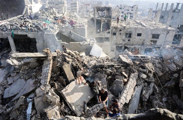 Palestinos intentan recuperar un cadáver de entre los escombros de una casa destruida en un ataque israelí durante la noche, en la ciudad de Gaza.