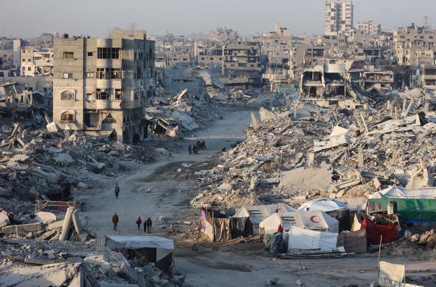 Palestinos caminan entre los escombros de edificios destruidos en el barrio de Sheikh Radwan, en la ciudad de Gaza.
