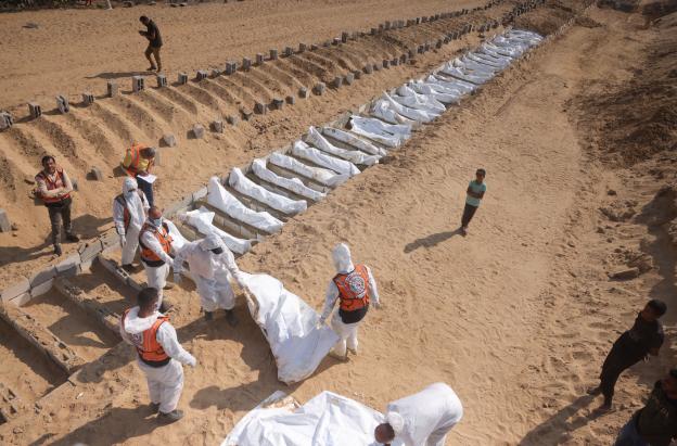 Trabajadores sanitarios y civiles realizan un entierro masivo de palestinos en un cementerio de Jan Yunis, en el sur de la Franja de Gaza.