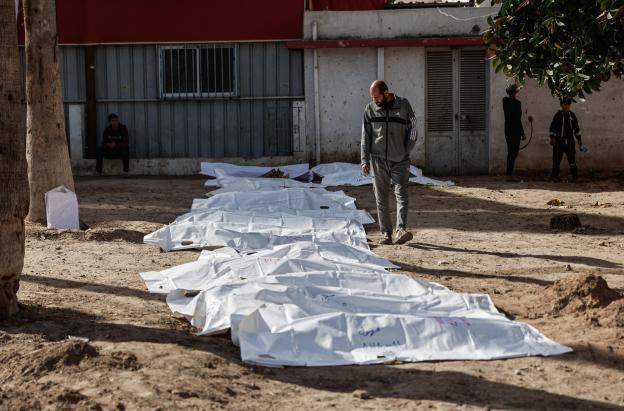 Un hombre observa las bolsas con restos humanos tras la exhumación de las tumbas por parte de la defensa civil en el interior del Hospital Bautista Árabe Al-Ahli para trasladar los restos a los cementerios oficiales de la ciudad de Gaza. 