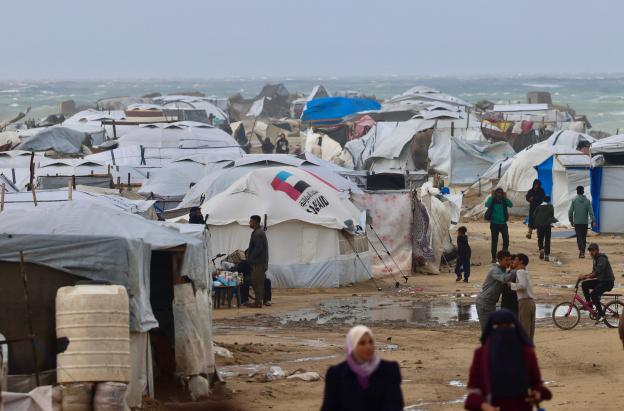 Los desplazados palestinos caminan cerca de tiendas de campaña y refugios improvisados mientras la región sufre las frías condiciones invernales en el campo de refugiados de Al-Mawasi, en el sur de la Franja de Gaza. 