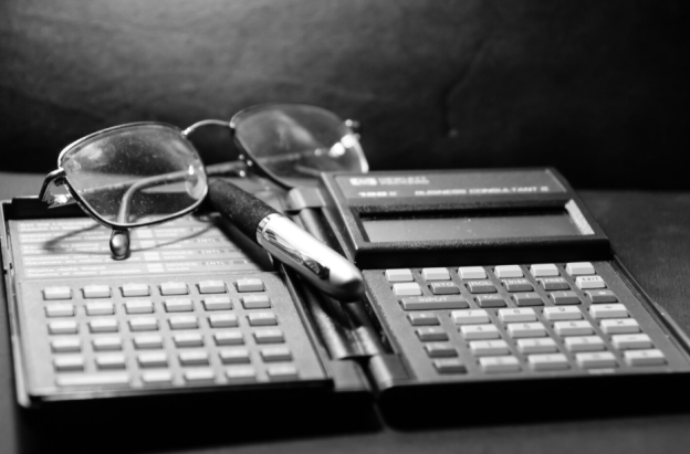 calculadora financiera antigua, gafas y lapicero