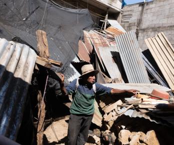 Mateo Rancho, de 70 años, permanece en el interior de su casa junto a la pared derrumbada de una tienda tras una serie de terremotos que sacudieron la zona en Santa María de Jesús, Guatemala.