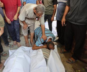 Un palestino llora sobre los cuerpos cubiertos con sábanas de sus familiares, muertos en un ataque israelí contra una panadería improvisada instalada en una tienda de campaña en la calle Al-Nassr, en la ciudad de Gaza.
