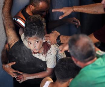 Palestinos transportan a un niño herido en el lugar donde se produjo un ataque israelí que destruyó varios edificios en el barrio de Al-Rimal, en la ciudad de Gaza.