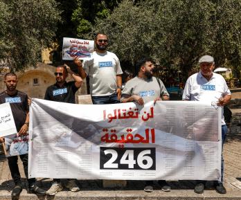Periodistas árabe-israelíes levantan pancartas y una bandera palestina durante una manifestación en solidaridad con sus compañeros de profesión fallecidos en los ataques israelíes en la Franja de Gaza, en la ciudad norteña de Nazaret, el