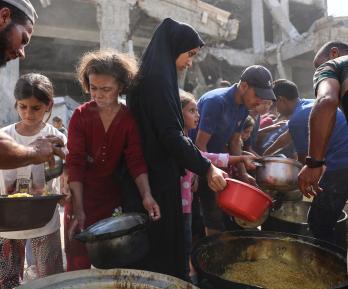 Los palestinos desplazados de Gaza se reúnen para recibir raciones de comida frente a la mezquita Imam al Shafi'i, dañada, donde se han refugiado familias, en el barrio de Zeitoun de la ciudad de Gaza.