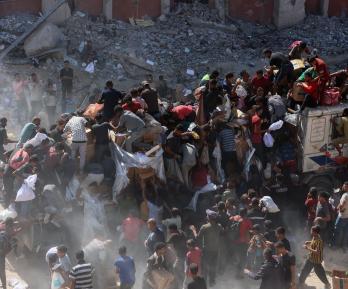 Los palestinos se apresuran a recibir paquetes de alimentos después de que los camiones de ayuda entraran por el paso fronterizo de Karem Abu Salem, en Jan Yunis, al sur de la Franja de Gaza.