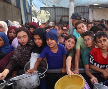 Niños palestinos se reúnen para recibir raciones de comida de un comedor benéfico en Nuseirat, en la Franja de Gaza central.