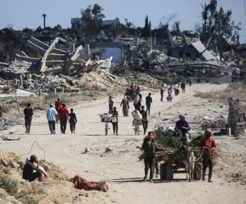 Vertriebene Palästinenser gehen an zerstörten Gebäuden vorbei, als sie in ihre Häuser im Gebiet al-Zahra nördlich des Flüchtlingslagers Nuseirat im zentralen Gazastreifen zurückkehren.