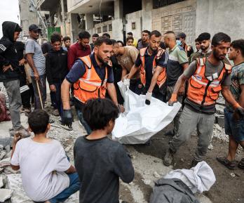 Palestinos transportan un cadáver que recuperaron de los escombros de una casa destruida en un ataque israelí perpetrado durante la noche en la ciudad de Gaza.