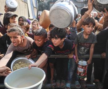 Jóvenes palestinos desplazados esperan con sus recipientes para recibir una ración de comida en el campo de refugiados de Nuseirat, en el centro de la Franja de Gaza, tras hambruna declarada por la ONU en el enclave. 