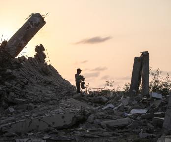 Un joven palestino recoge un trozo de escombro en Nuseirat, durante el genocidio palestino perpetrado por Israel, blanqueado por influencers colombianos