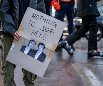 Un manifestante sostiene una pancarta con fotografías de Jeffrey Epstein (izquierda), un acaudalado financiero estadounidense que murió en prisión en 2019 mientras esperaba juicio por tráfico sexual de menores, y del presidente de Estados Unidos, Donald Trump (derecha), durante una manifestación contra el Foro Económico Mundial (FEM) en vísperas de la reunión anual del FEM en Davos.