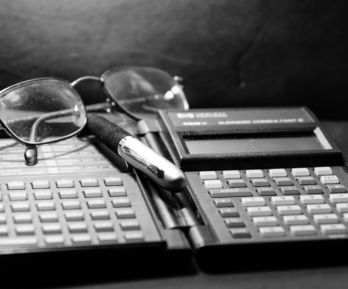 calculadora financiera antigua, gafas y lapicero