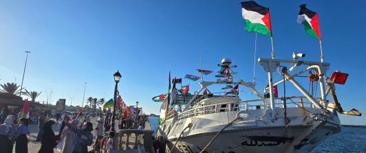 Personas posan para una foto frente al barco Omar al-Mukhtar, un barco libio que zarpó el 17 de septiembre para unirse a la Flotilla Global Sumud, en el puerto de Trípoli.