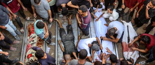 La gente rodea los cadáveres de palestinos, algunos muertos en los ataques israelíes de madrugada y otros asesinados el día anterior mientras buscaban ayuda humanitaria cerca de Zikim, al oeste de Beit Lahia, en el patio del hospital al-Shifa de la ciudad de Gaza.