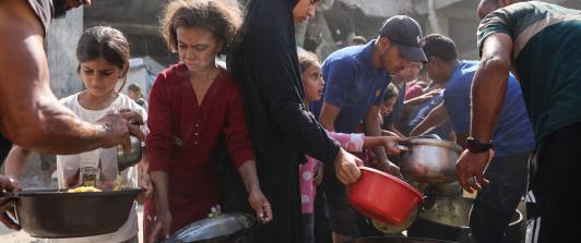 Los palestinos desplazados de Gaza se reúnen para recibir raciones de comida frente a la mezquita Imam al Shafi'i, dañada, donde se han refugiado familias, en el barrio de Zeitoun de la ciudad de Gaza.