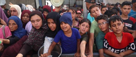 Niños palestinos se reúnen para recibir raciones de comida de un comedor benéfico en Nuseirat, en la Franja de Gaza central.