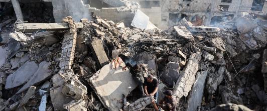 Palestinos intentan recuperar un cadáver de entre los escombros de una casa destruida en un ataque israelí durante la noche, en la ciudad de Gaza.
