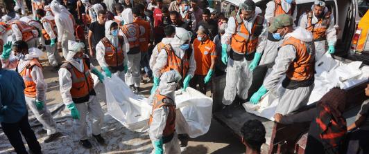 Miembros de Defensa Civil descargan bolsas con los restos mortales de los miembros de la familia Shahebar, que fueron enterrados en tumbas temporales, mientras son trasladados al cementerio Sheikh Shaaban, en la ciudad de Gaza, el 24 de octubre.