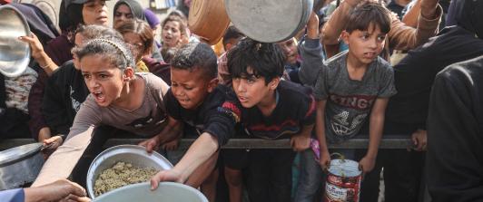 Jóvenes palestinos desplazados esperan con sus recipientes para recibir una ración de comida en el campo de refugiados de Nuseirat, en el centro de la Franja de Gaza, tras hambruna declarada por la ONU en el enclave. 