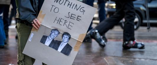 Un manifestante sostiene una pancarta con fotografías de Jeffrey Epstein (izquierda), un acaudalado financiero estadounidense que murió en prisión en 2019 mientras esperaba juicio por tráfico sexual de menores, y del presidente de Estados Unidos, Donald Trump (derecha), durante una manifestación contra el Foro Económico Mundial (FEM) en vísperas de la reunión anual del FEM en Davos.