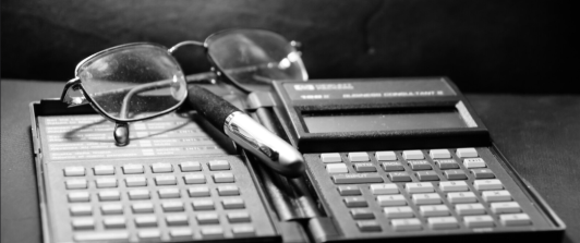 calculadora financiera antigua, gafas y lapicero