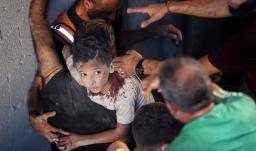 Palestinos transportan a un niño herido en el lugar donde se produjo un ataque israelí que destruyó varios edificios en el barrio de Al-Rimal, en la ciudad de Gaza.